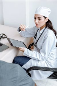 medical professional sitting on a chair holding a tablet while talking